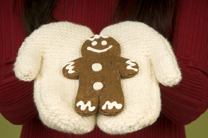 Close up of woman in mittens holding gingerbread man